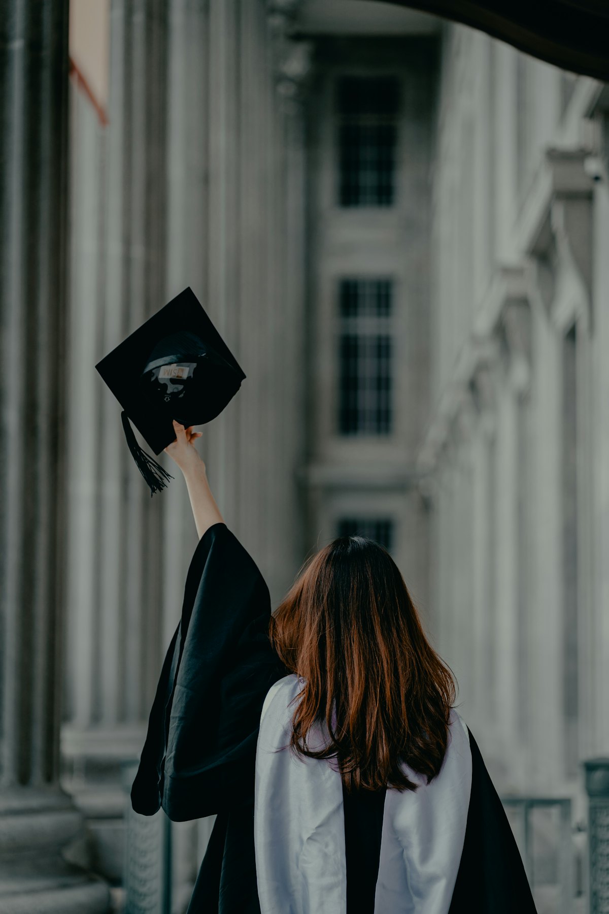 毕业生在古典柱廊建筑前高举学位帽