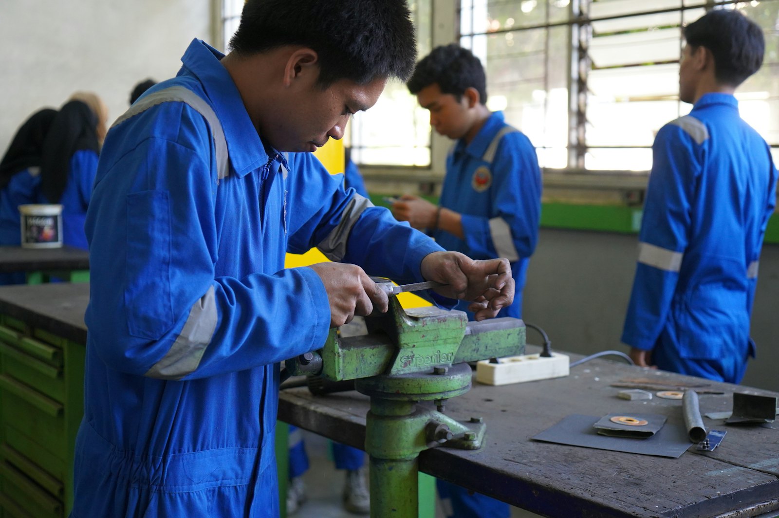 技工学院课堂实训场景,学生在动手操作金属加工工具
