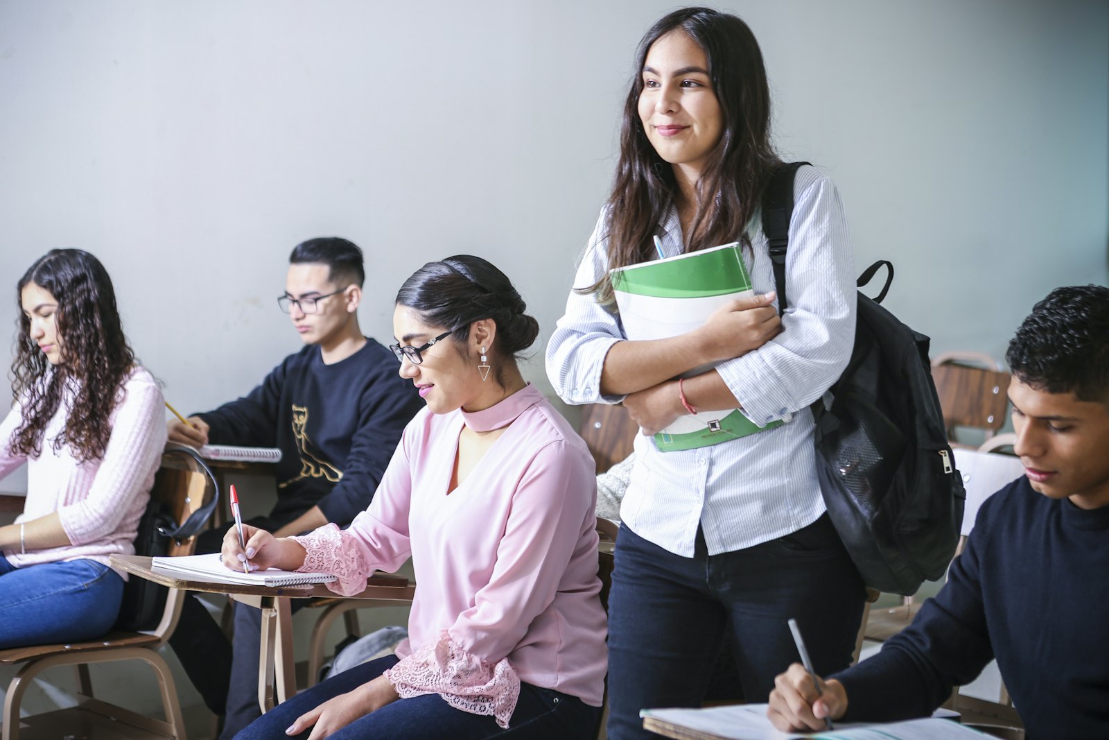 加拿大高中学生在教室里学习，手持课本交流