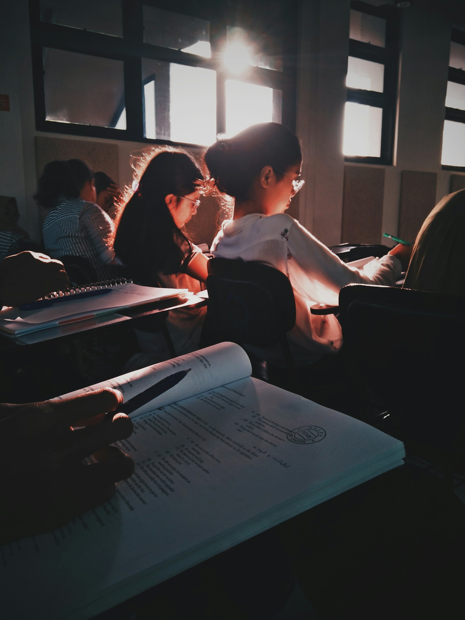 学生在教室里认真看书写字，阳光从窗户射入课室