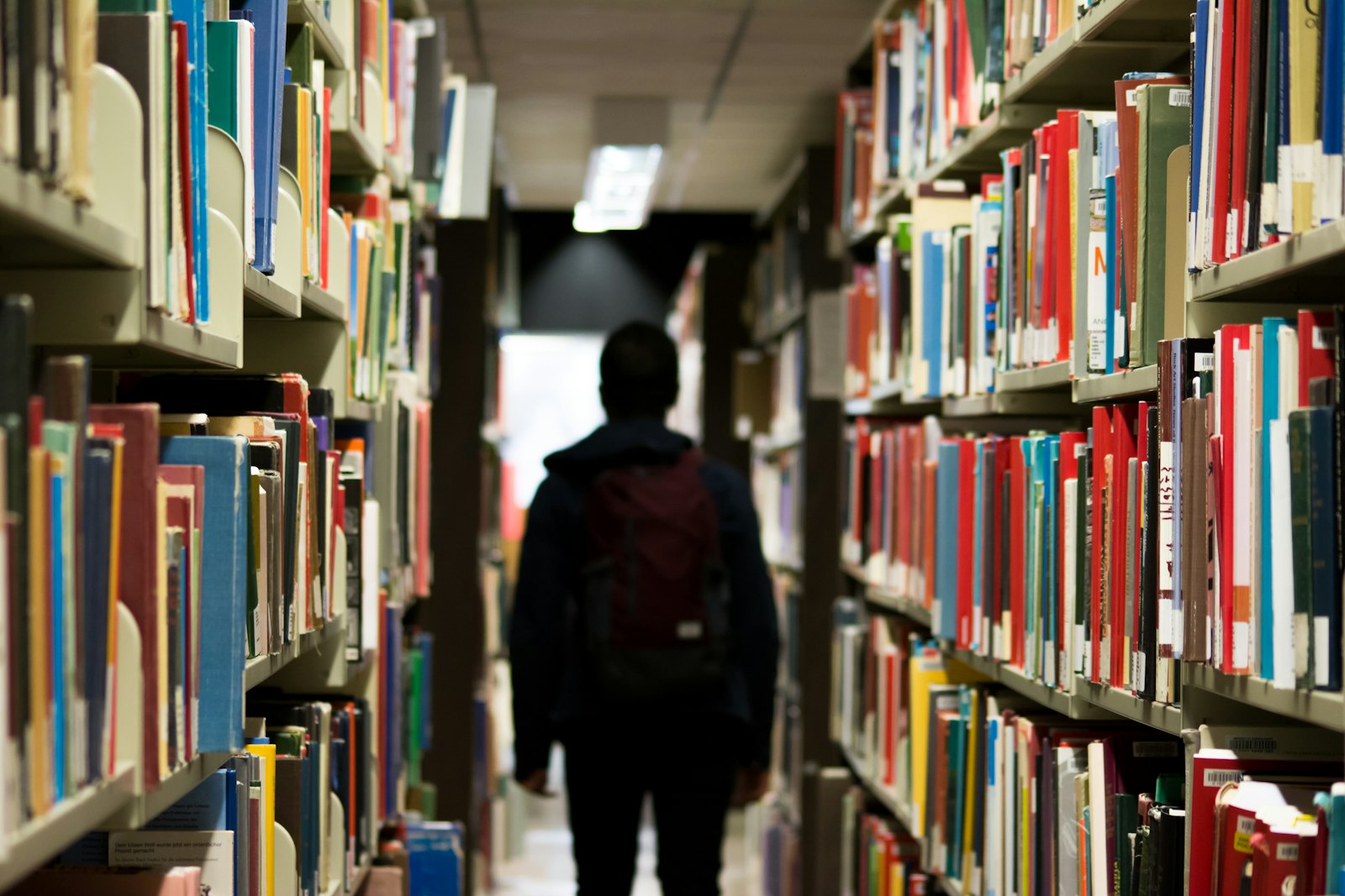 学生在学校图书馆内走动，背负书包